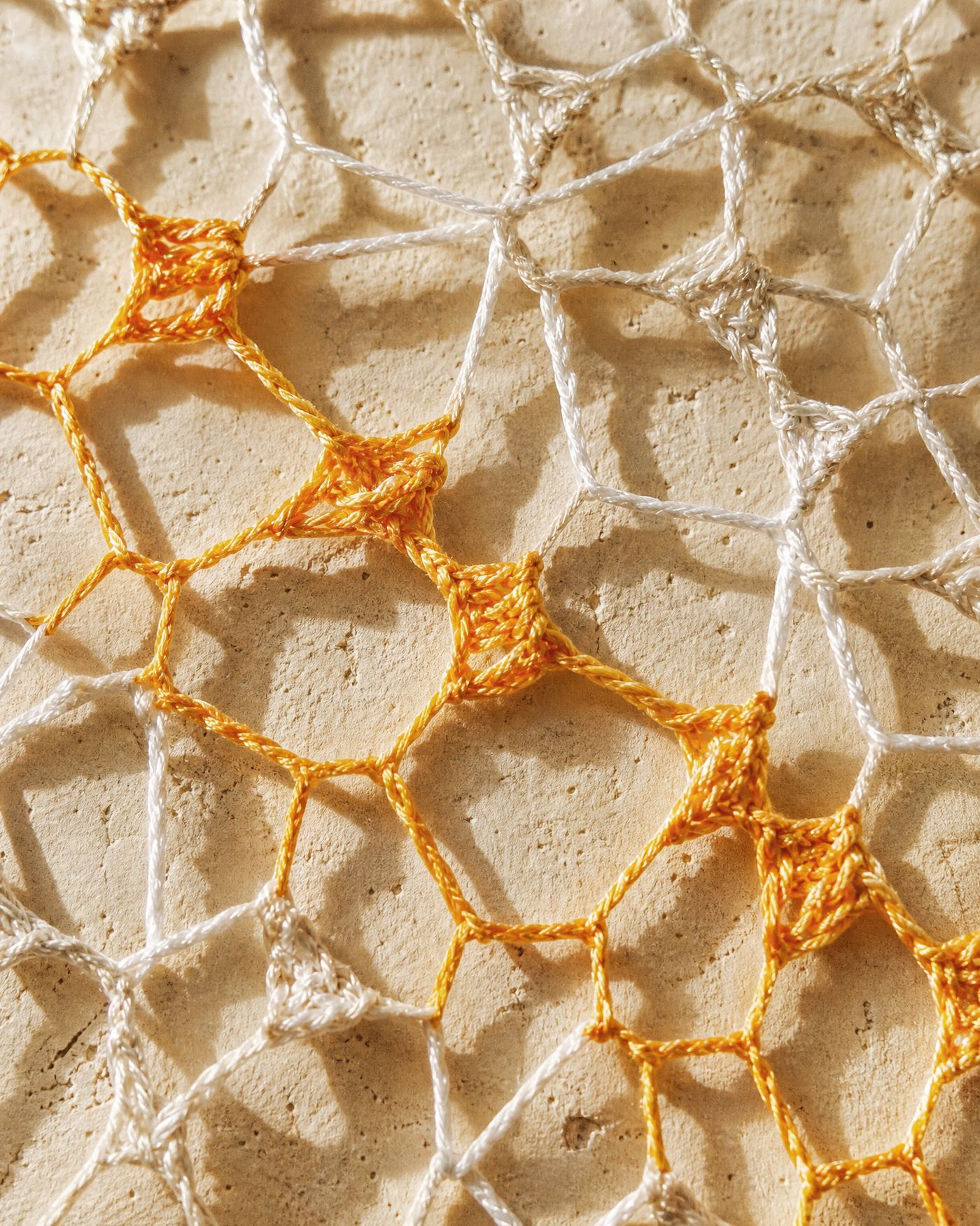 Macro detail of hand-knotted thread forming the concentric weave, showing individual knots and thread tension.