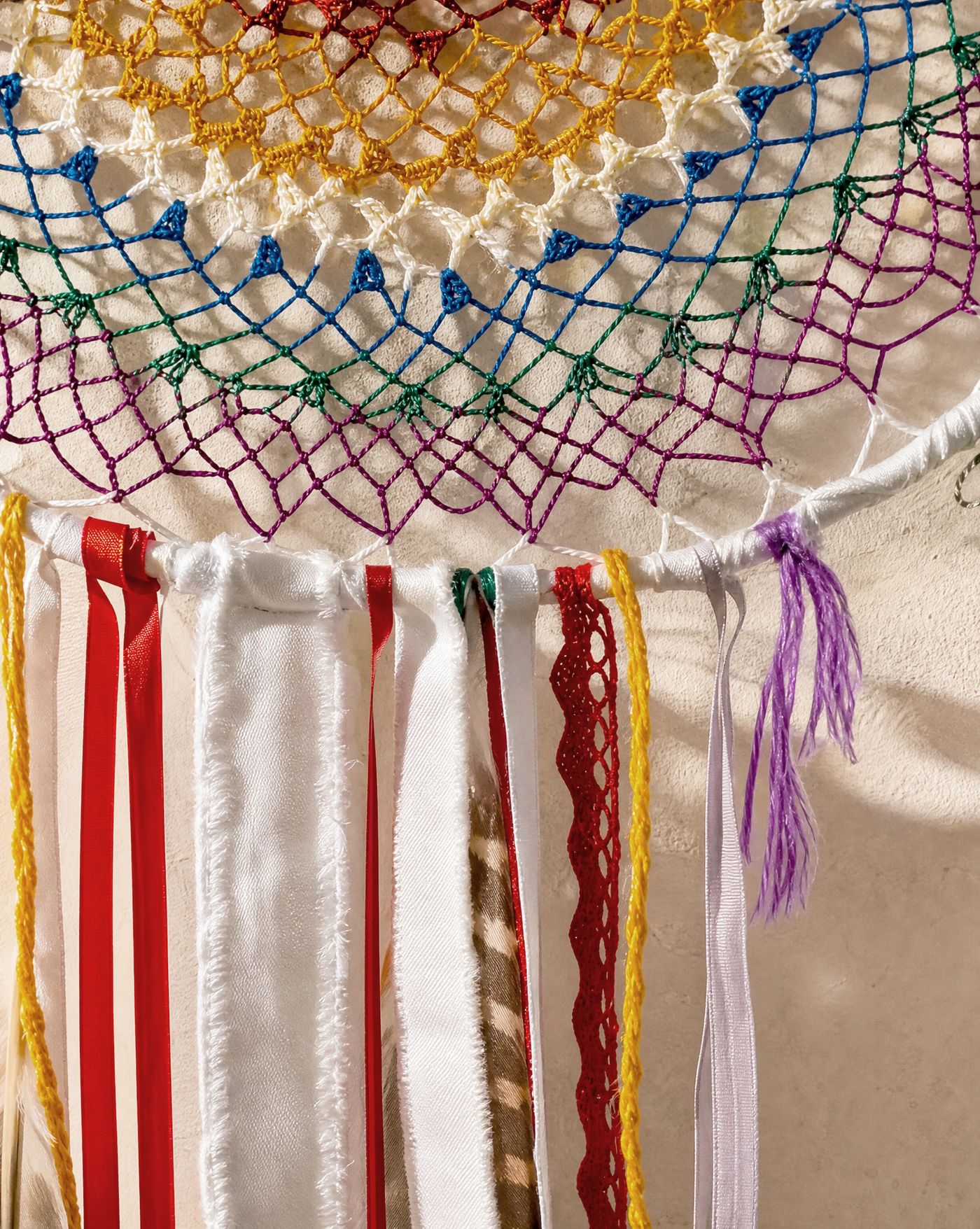 Close detail study of the ribbon and lace fringe hanging from The Watcher, with a barred feather visible among the ribbons.