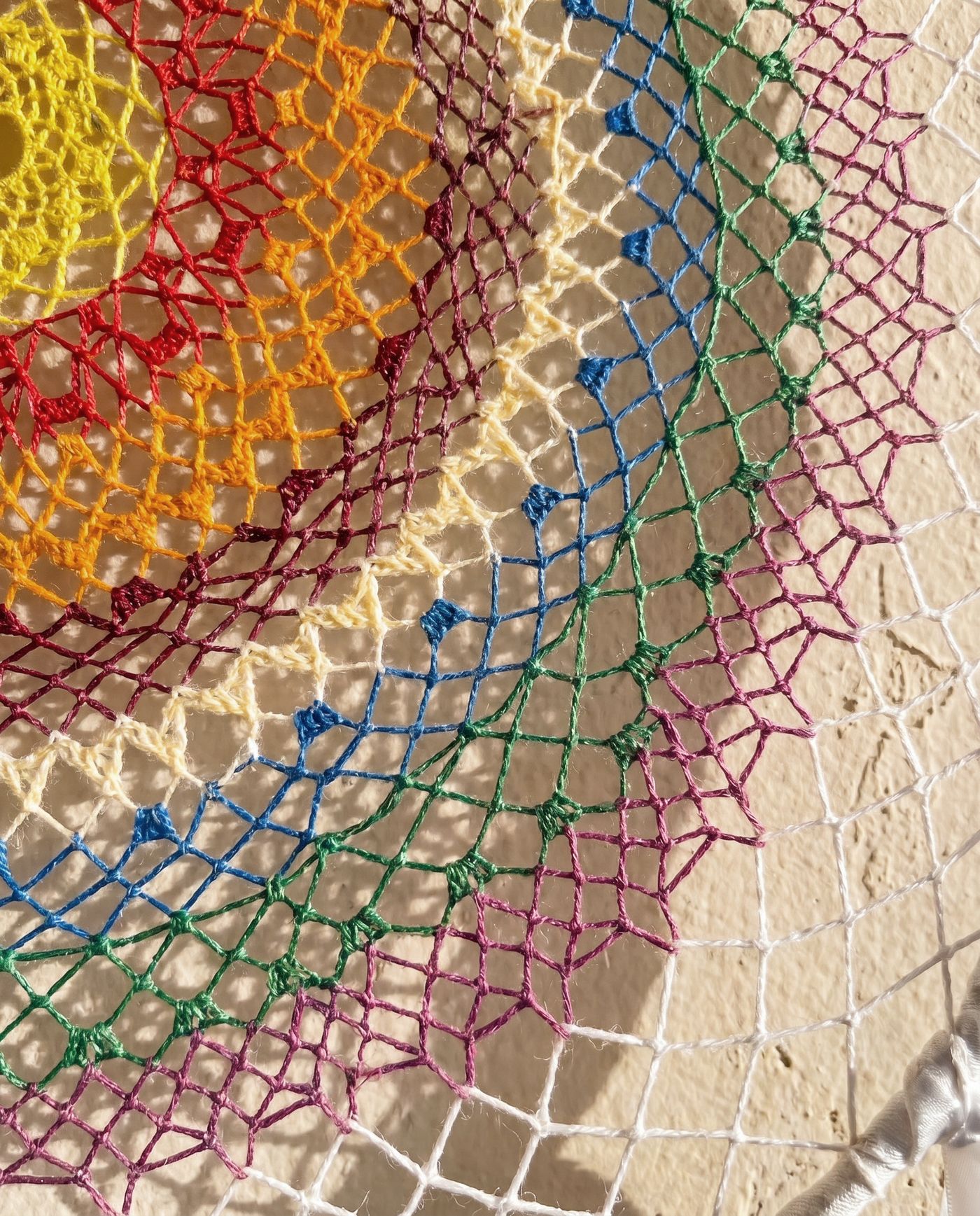 Macro detail of a multicoloured hand-knotted weave, showing the transition between colour bands.
